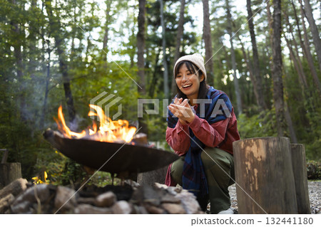 A woman making a bonfire at a campsite A woman making a bonfire at a campsite 132441180
