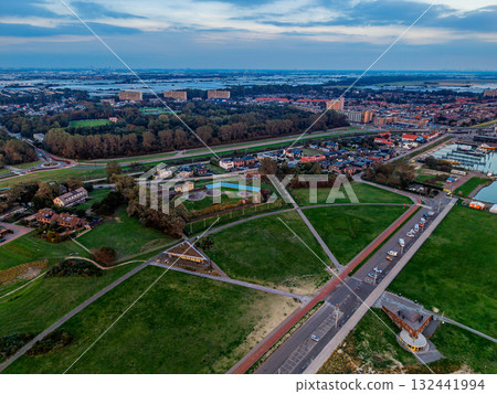 Aerial view of coastal urban park sandy beach, promenade, triangular pavilion, circular playgrounds, and dense residential blocks near river blend recreation, architecture, and shoreline planning. Aerial view of coastal urban park sandy beach, promenade, triangular pavilion, circular playgrounds, and dense residential blocks near river blend recreation, architecture, and shoreline planning. 132441994