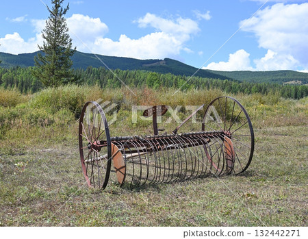 Old farm hay mower in a field Old farm hay mower in a field 132442271