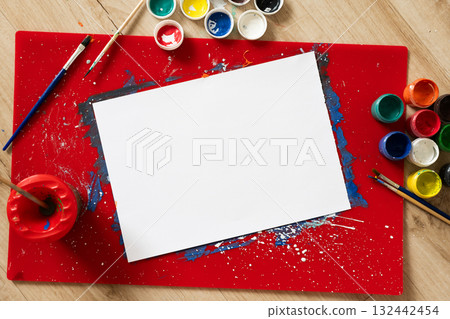 Blank canvas on red art palette with colorful paint and brushes nearby 132442454