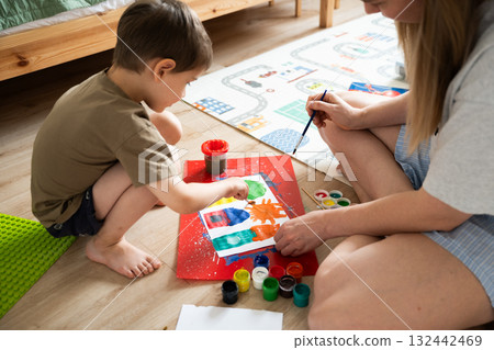 Child painting with mother in creative indoor space with colorful materials Child painting with mother in creative indoor space with colorful materials 132442469