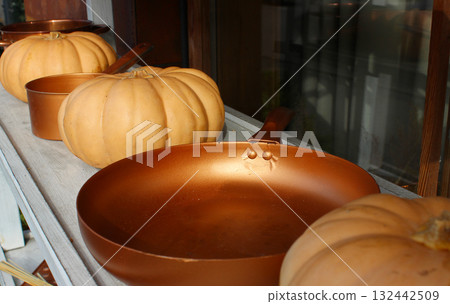 A shelf at a country fair adorned with vintage copper cooking utensils nestled between ripe pumpkins A shelf at a country fair adorned with vintage copper cooking utensils nestled between ripe pumpkins 132442509