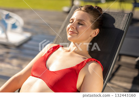 Cute young woman in red swimsuit sunbathing and looking peaceful Cute young woman in red swimsuit sunbathing and looking peaceful 132443160