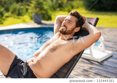 Bearded handsome man lying on a chair near the swimming pool 132443161