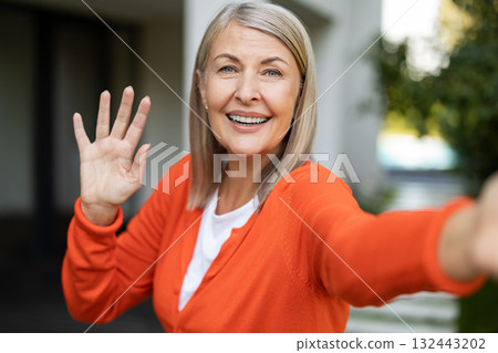 Mature pretty woman feeling excited and waving her hand while having a video call 132443202