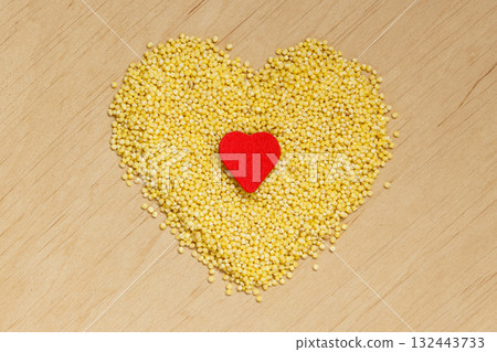 Millet groats heart shaped on wooden surface. Millet groats heart shaped on wooden surface. 132443733