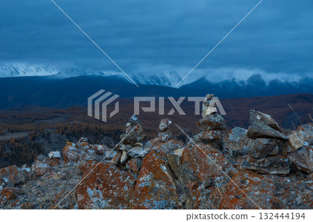 Stacked stones on mountain landscape with dramatic sky and distant peaks 132444194
