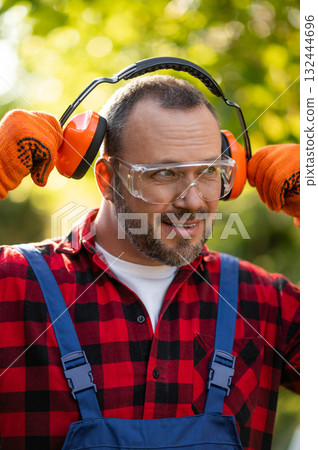 Professional landscaper putting on protective earmuffs Professional landscaper putting on protective earmuffs 132444696
