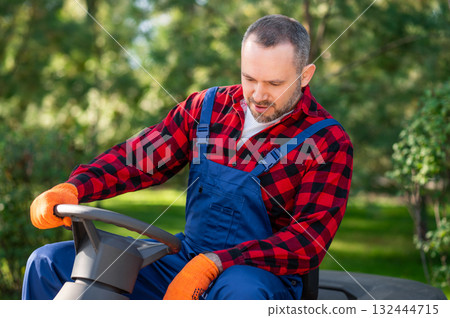 Gardener sitting in driver seat of small garden vehicle 132444715