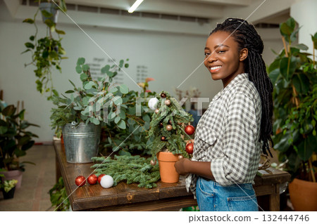 Long-haired african american woman looking contented while working in a flower shop 132444746