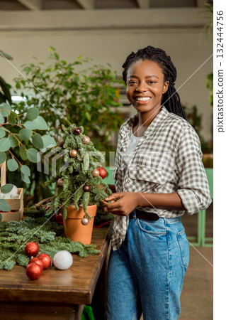 Long-haired african american woman looking contented while working in a flower shop 132444756