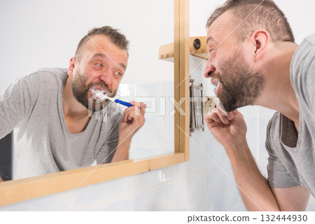 Bored guy brushing his teeth in bathroom Bored guy brushing his teeth in bathroom 132444930