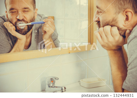 Bored guy brushing his teeth in bathroom 132444931