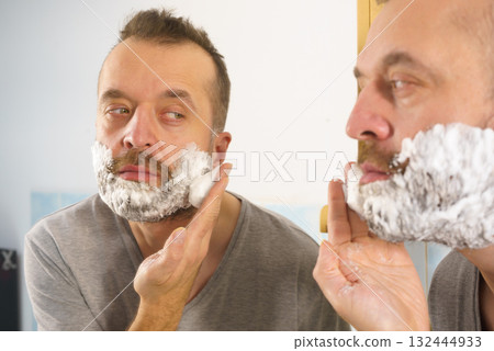 Guy shaving his beard in bathroom Guy shaving his beard in bathroom 132444933
