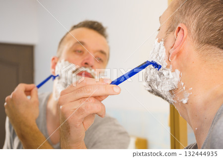 Guy shaving his beard in bathroom Guy shaving his beard in bathroom 132444935