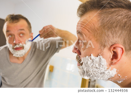 Guy shaving his beard in bathroom 132444936