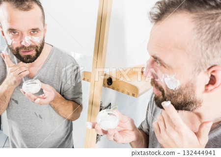 Man applying moisturizer cream in bathroom Man applying moisturizer cream in bathroom 132444941