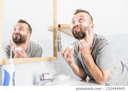Man applying moisturizer cream in bathroom Man applying moisturizer cream in bathroom 132444943