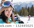 A smiling woman riding a chairlift on a sunny snowy mountain 132445025