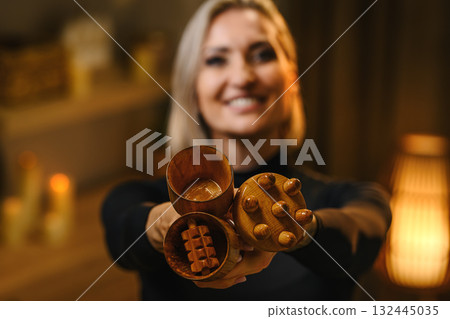 Professional woman therapist performing wood therapy massage for cellulite reduction and body sculpting. 132445035