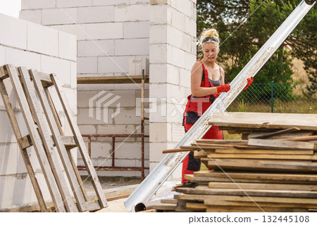 Woman carrying gutter on construction site Woman carrying gutter on construction site 132445108