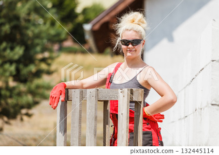 Woman in dungarees working on construction site Woman in dungarees working on construction site 132445114