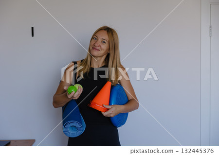 fit professional getting ready for class, active instructor in bright room preparing fitness session 132445376