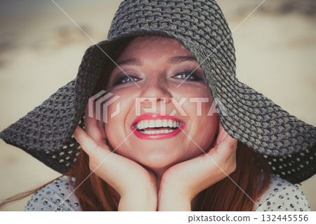 Happy redhead woman wearing big black sun hat 132445556