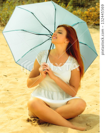 Beautiful redhaired girl with umbrella on beach. 132445569
