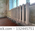 Old cast-iron heating battery near window in room that is undergoing renovation 132445751