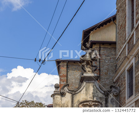 Baroque statue of Saint George slaying dragon crowns weathered facade in bright Bergamo sky Baroque statue of Saint George slaying dragon crowns weathered facade in bright Bergamo sky 132445772