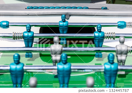 Foosball players in symmetrical formation face the goal on vivid green field with metallic shine Foosball players in symmetrical formation face the goal on vivid green field with metallic shine 132445787