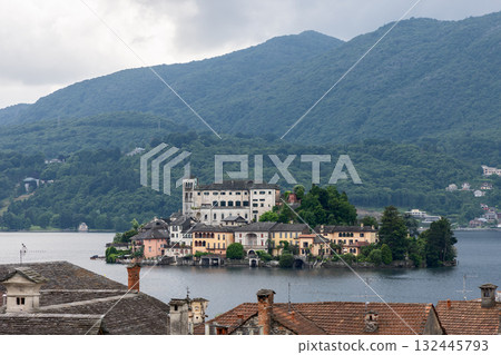 San Giulio Island on Lake Orta with colorful buildings basilica and misty green hills in background San Giulio Island on Lake Orta with colorful buildings basilica and misty green hills in background 132445793