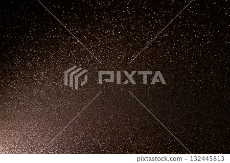 Rich brown glitter surface glowing from lower left with sparkles fading into festive darkness 132445813