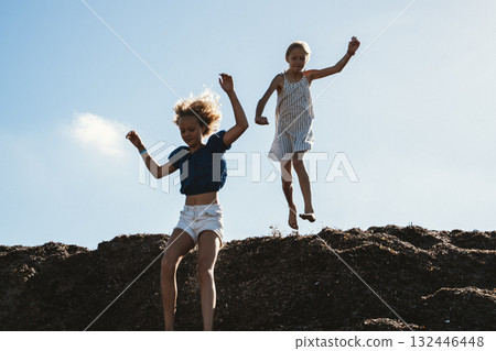 Girls Joyfully Jumping from Seaweed Pile at the Shore 132446448
