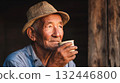 Elderly man enjoying warm drink while reflecting and relaxing in natural light at home during a peaceful afternoon 132446800