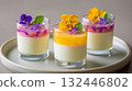 Colorful dessert cups with edible flowers and creamy layers served on a round plate 132446802