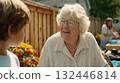 Elderly woman shares a joyful conversation with a young boy in a vibrant garden filled with colorful flowers during a sunny day in a friendly neighborhood 132446814