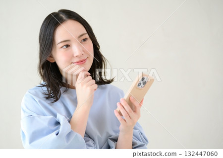 A worried Japanese woman looking at her smartphone A worried Japanese woman looking at her smartphone 132447060
