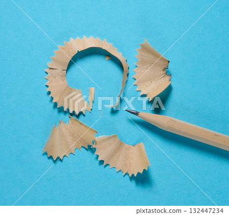 A wooden pencil and several neat curls of pencil shavings on a blue background A wooden pencil and several neat curls of pencil shavings on a blue background 132447234