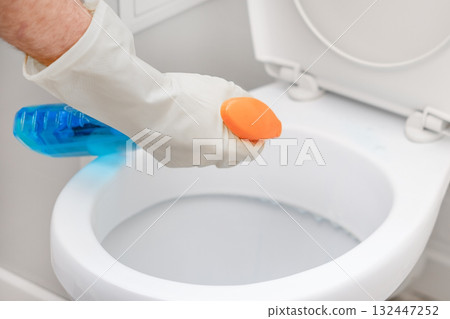 A man washes a toilet. He cleans the toilet to maintain cleanliness and hygiene 132447252