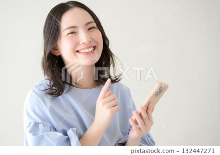Japanese woman holding a smartphone and looking at the camera 132447271