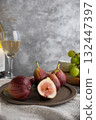 A plate of sliced figs, Shine Muscat grapes, cheese, and wine are lined up on the table. 132447397