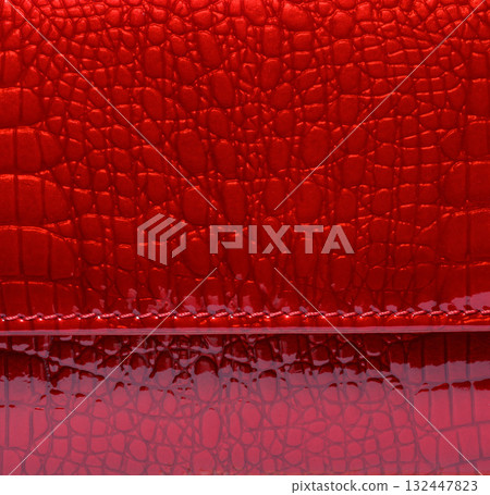 Texture of red glossy artificial leather with imitation crocodile skin and seam 132447823