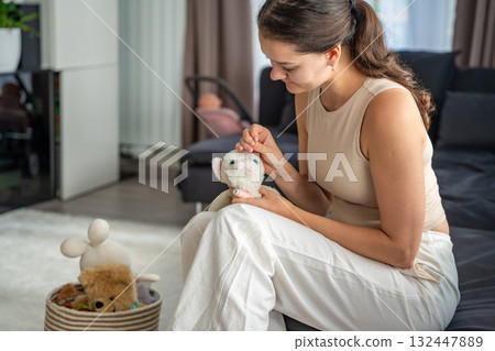 Young woman sewing an old plush toy at home with needle and thread. Sustainable lifestyle and conscious consumption as part of eco friendly and mindful living. Young woman sewing an old plush toy at home with needle and thread. Sustainable lifestyle and conscious consumption as part of eco friendly and mindful living. 132447889