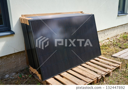 Stack of new solar panels with protective cardboard, ready for installation. Renewable energy, sustainable home improvements, and eco-friendly investments in residential property infrastructure. Stack of new solar panels with protective cardboard, ready for installation. Renewable energy, sustainable home improvements, and eco-friendly investments in residential property infrastructure. 132447892
