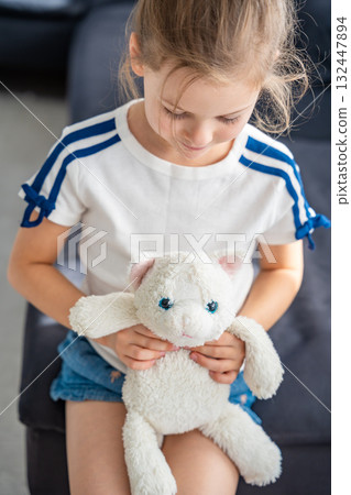 Portrait of a child holding a well-worn soft toy in their hands. Emotional attachment to a beloved object that brings comfort, trust, and a feeling of safety in early childhood. Portrait of a child holding a well-worn soft toy in their hands. Emotional attachment to a beloved object that brings comfort, trust, and a feeling of safety in early childhood. 132447894