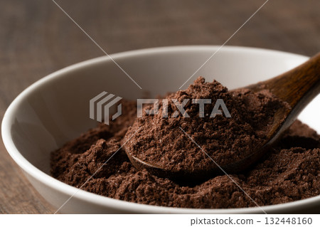 Close-up of cocoa powder with sugar in a spoon on a small plate Close-up of cocoa powder with sugar in a spoon on a small plate 132448160