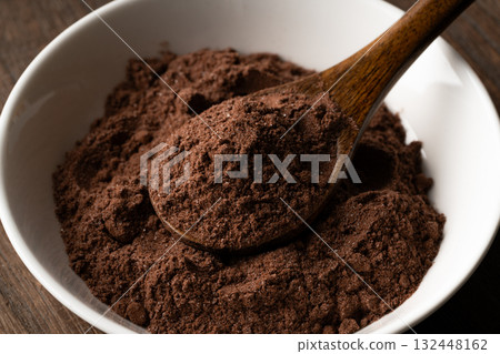 Close-up of cocoa powder with sugar in a spoon on a small plate Close-up of cocoa powder with sugar in a spoon on a small plate 132448162