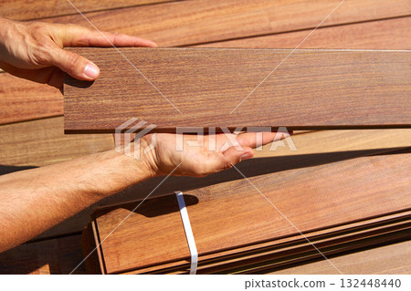 Ipe deck installation carpenter hands holding wood 132448440